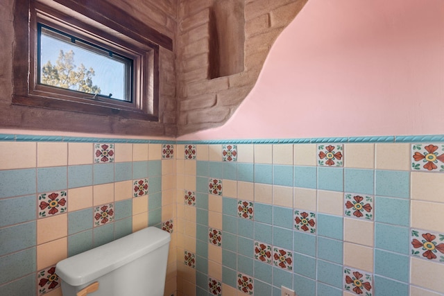 bathroom featuring tile walls and toilet