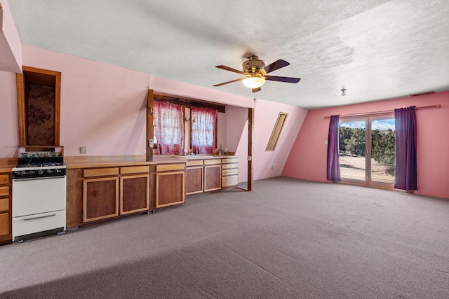 interior space featuring sink, gas range gas stove, a textured ceiling, carpet flooring, and ceiling fan