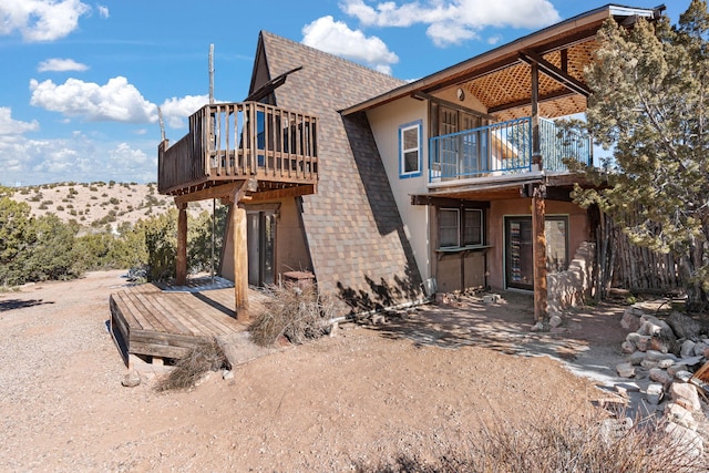 rear view of house featuring a balcony and a deck with mountain view