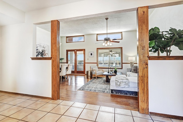 living room with ceiling fan, light tile patterned floors, and a textured ceiling