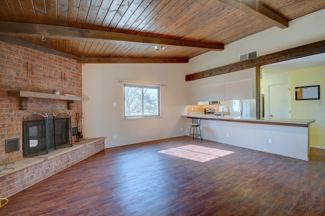 unfurnished living room featuring dark wood-type flooring, sink, a brick fireplace, wooden ceiling, and beam ceiling