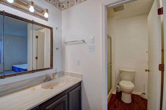 bathroom featuring wood-type flooring, toilet, a shower with shower door, and vanity