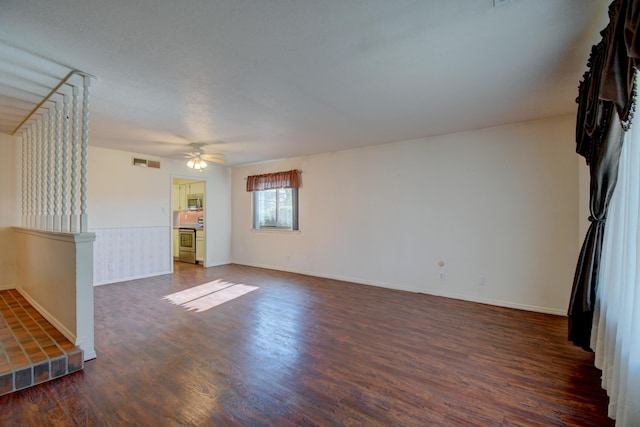 unfurnished living room featuring dark wood-type flooring and ceiling fan