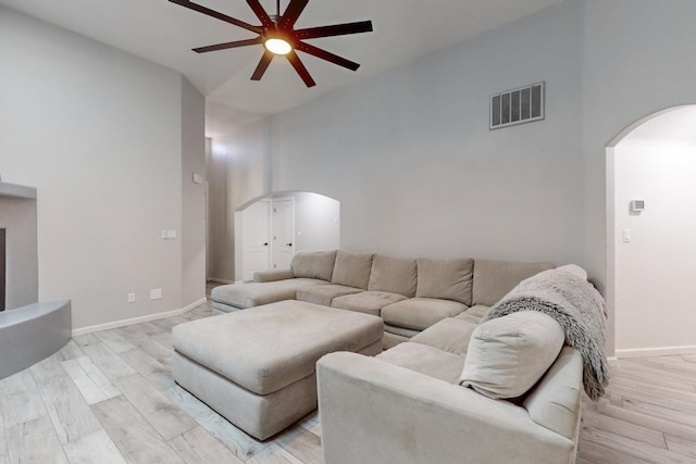 living room with a high ceiling, ceiling fan, and light hardwood / wood-style floors