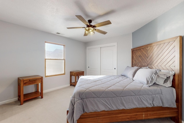 bedroom featuring light carpet, a textured ceiling, a closet, and ceiling fan