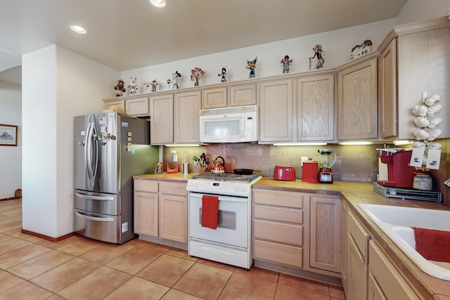 kitchen featuring sink, light tile patterned floors, backsplash, and white appliances