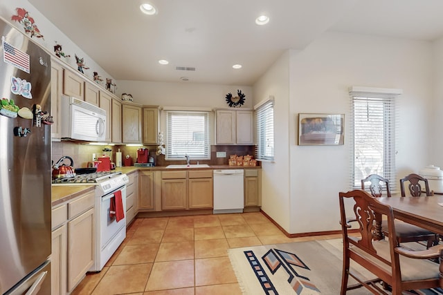 kitchen with light tile patterned flooring, light brown cabinetry, sink, decorative backsplash, and white appliances