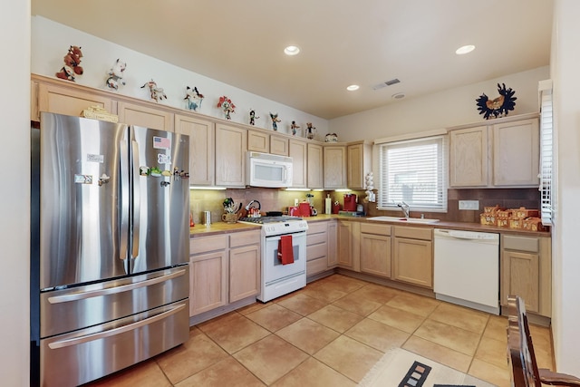 kitchen with light tile patterned flooring, sink, light brown cabinets, white appliances, and backsplash