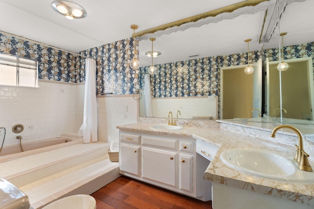 bathroom with hardwood / wood-style flooring, vanity, a bathing tub, and tile walls