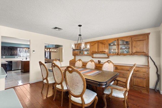 dining space with hardwood / wood-style floors, a chandelier, and a textured ceiling