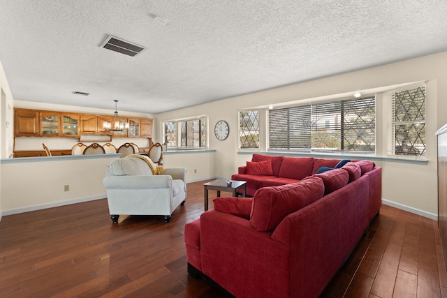 living room with an inviting chandelier, dark hardwood / wood-style floors, and a textured ceiling