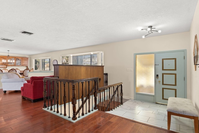 corridor featuring a textured ceiling, dark hardwood / wood-style floors, and a chandelier