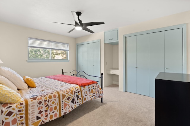 bedroom featuring two closets, light colored carpet, and ceiling fan