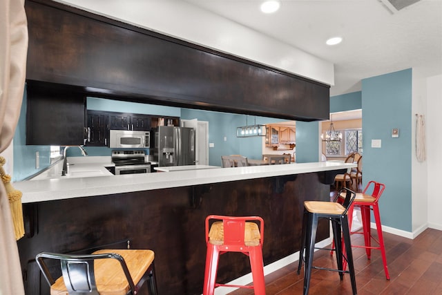 kitchen featuring sink, a breakfast bar, appliances with stainless steel finishes, dark hardwood / wood-style floors, and kitchen peninsula