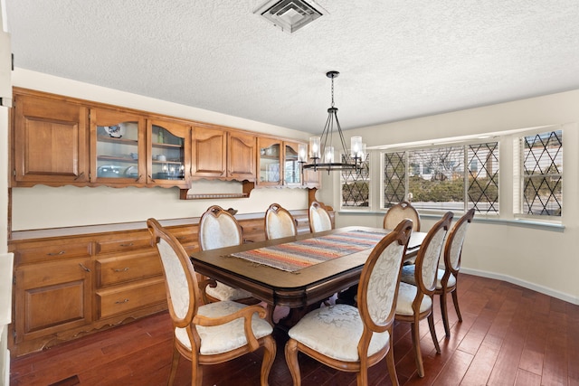 dining room with dark hardwood / wood-style floors, a chandelier, and a textured ceiling