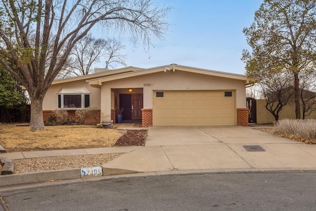 view of front of property with brick siding, stucco siding, an attached garage, and concrete driveway