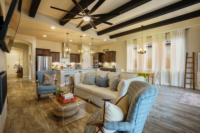 living room featuring dark hardwood / wood-style flooring, ceiling fan with notable chandelier, and beam ceiling