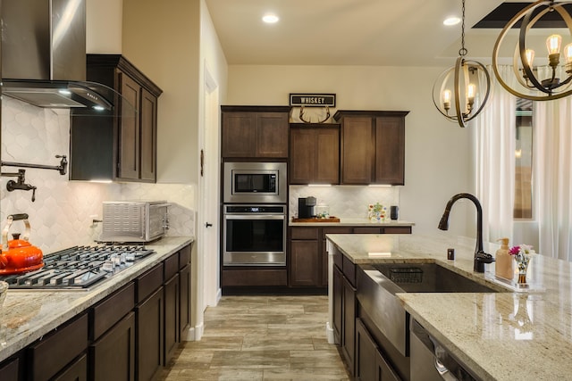 kitchen featuring light stone counters, wall chimney range hood, stainless steel appliances, and dark brown cabinetry