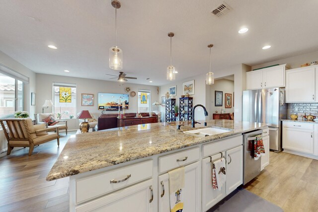 kitchen with stainless steel appliances, sink, a center island with sink, and white cabinets