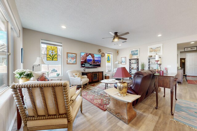 living room with ceiling fan, light hardwood / wood-style flooring, and a textured ceiling