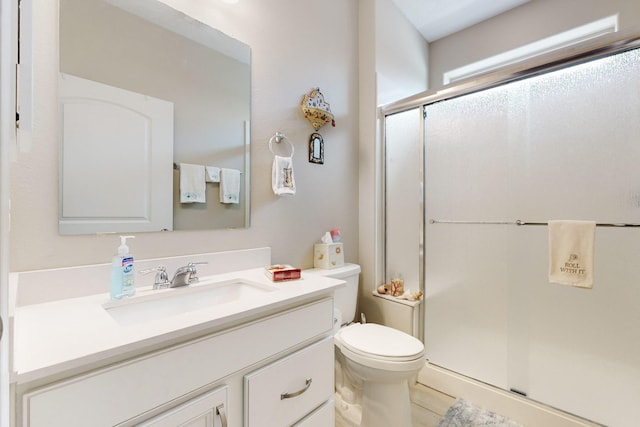 bathroom featuring a shower with door, vanity, and toilet