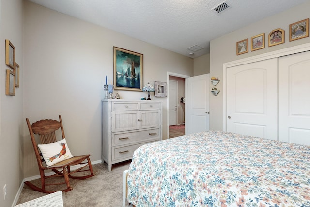 bedroom with light colored carpet, a textured ceiling, and a closet