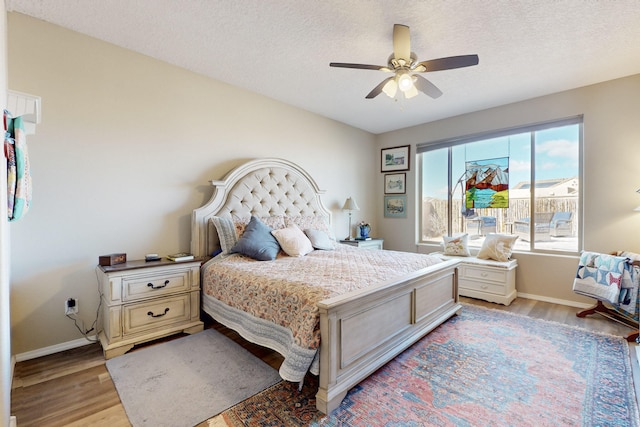 bedroom with ceiling fan, a textured ceiling, and light hardwood / wood-style floors