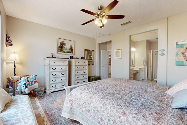 bedroom featuring ceiling fan, ensuite bathroom, and a textured ceiling