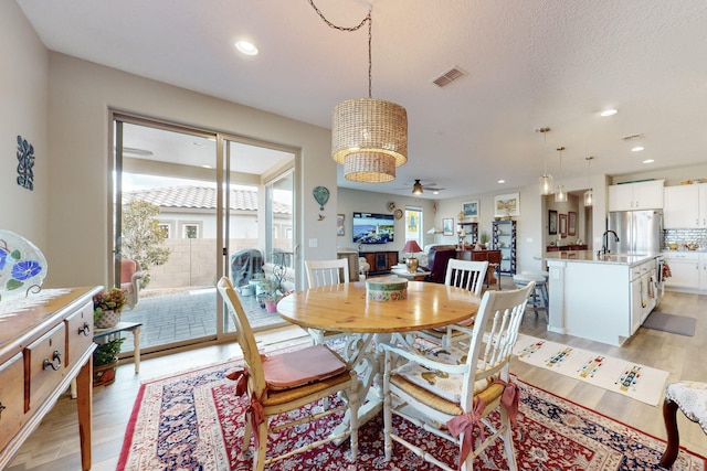 dining space with ceiling fan, light hardwood / wood-style flooring, and a textured ceiling