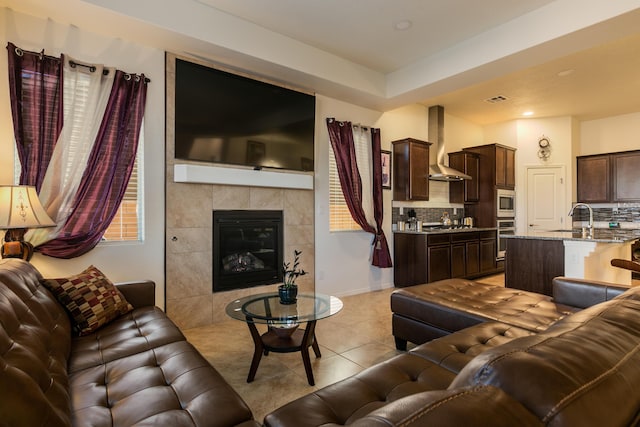 living area featuring light tile patterned floors, baseboards, visible vents, and a tile fireplace