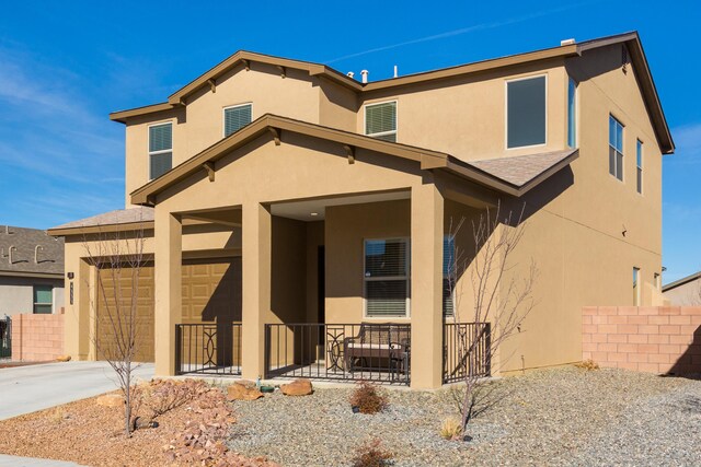 view of front of house with stucco siding, covered porch, an attached garage, fence, and driveway