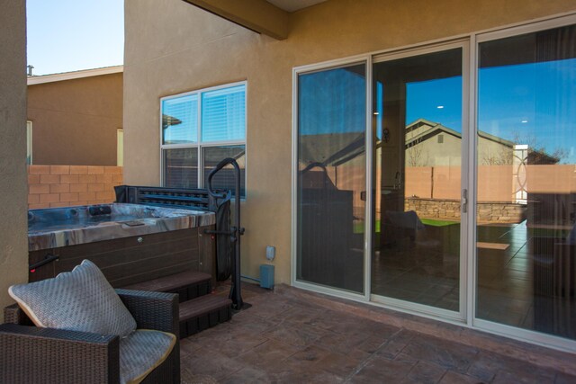 view of patio featuring fence and a hot tub