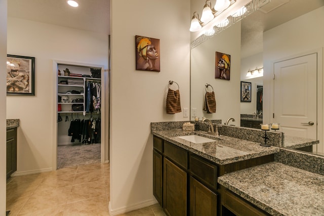 full bath featuring tile patterned flooring, a walk in closet, vanity, and baseboards