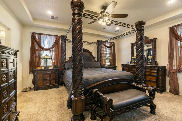 carpeted bedroom with baseboards, visible vents, a raised ceiling, and a textured ceiling