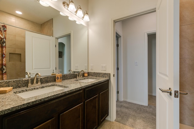 bathroom with tile patterned floors, a sink, baseboards, and double vanity