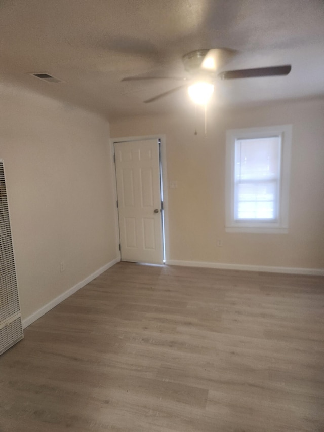 empty room featuring ceiling fan, a textured ceiling, and light wood-type flooring