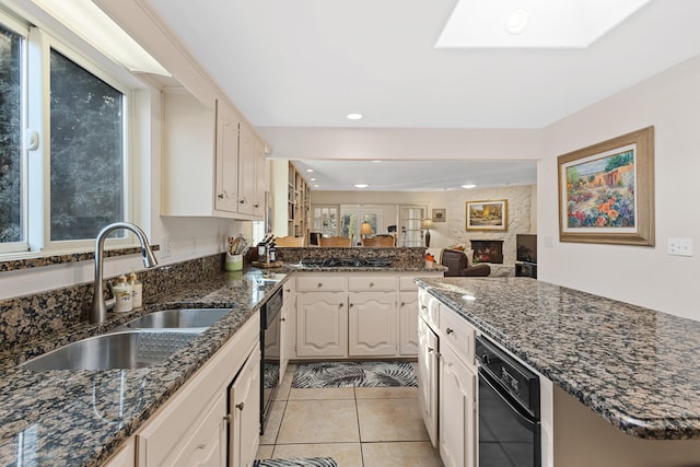 kitchen with a fireplace, dishwasher, sink, light tile patterned floors, and kitchen peninsula