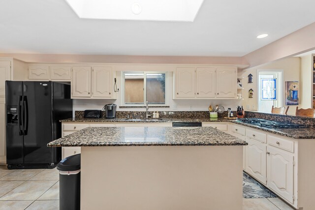 kitchen featuring white cabinetry, sink, black appliances, and dark stone counters