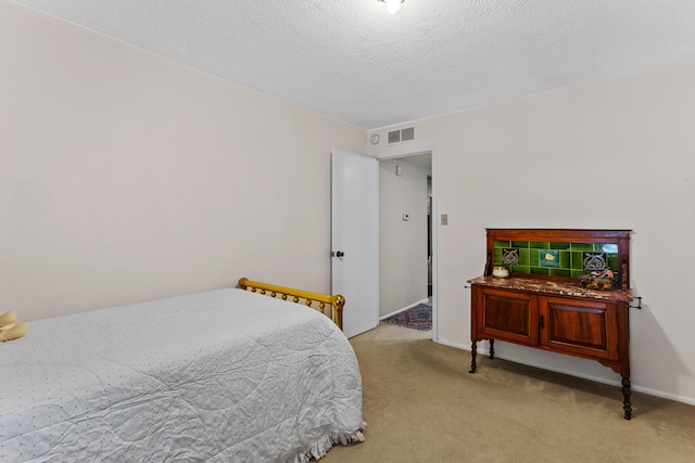 bedroom with light colored carpet and a textured ceiling