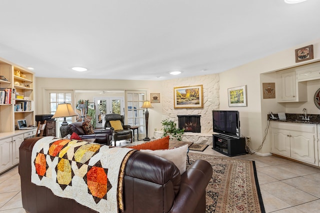 tiled living room featuring sink, a fireplace, and french doors