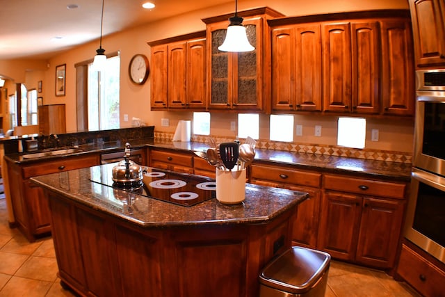 kitchen featuring sink, a kitchen island, black electric cooktop, decorative light fixtures, and kitchen peninsula