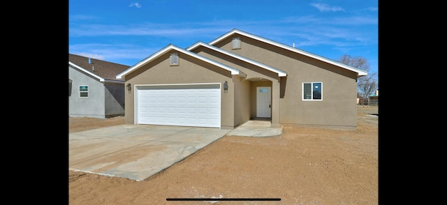 view of front of property featuring stucco siding, driveway, and a garage