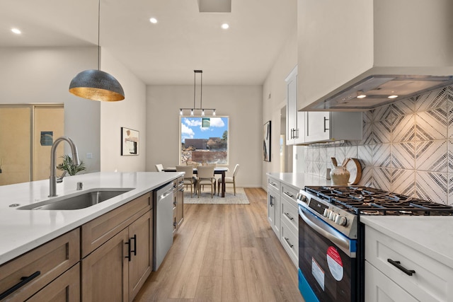 kitchen featuring appliances with stainless steel finishes, exhaust hood, white cabinets, and decorative light fixtures