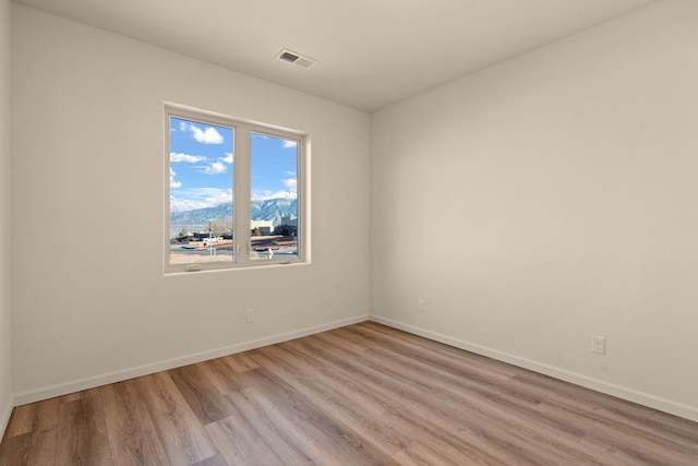 spare room with a mountain view and light hardwood / wood-style floors