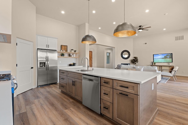 kitchen featuring sink, white cabinetry, hanging light fixtures, stainless steel appliances, and an island with sink