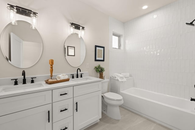 full bathroom featuring tiled shower / bath, vanity, and toilet