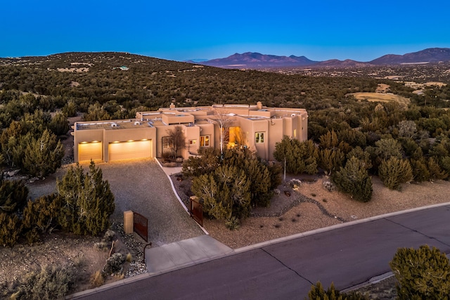 view of front of property with a mountain view, driveway, an attached garage, and stucco siding