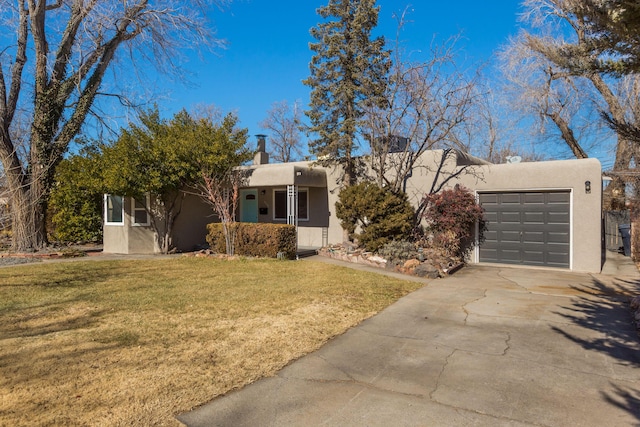 pueblo revival-style home with a garage and a front lawn