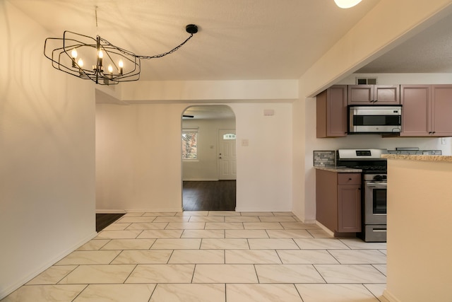 kitchen with pendant lighting, stainless steel appliances, and a notable chandelier