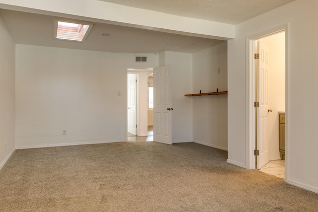 carpeted empty room featuring a skylight